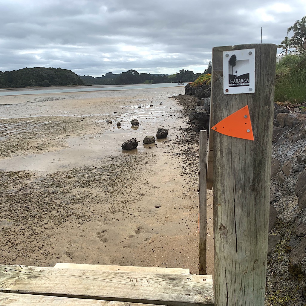 The Te Araroa sign points down stairs and to Nikau Bay, but it can only be crossed by boat.