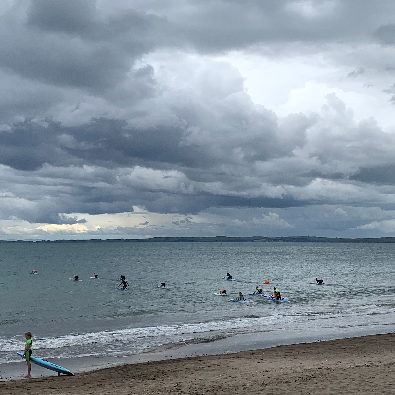 Kids taking out surf boards in one of the many bays along the North Shore. Storm clouds make no difference since it rains nearly every day. 