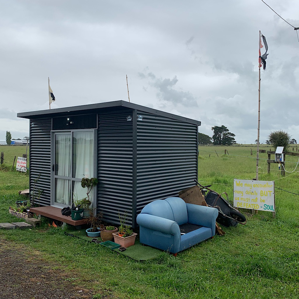 A tiny container house of a land-use protester with his living room outside. 