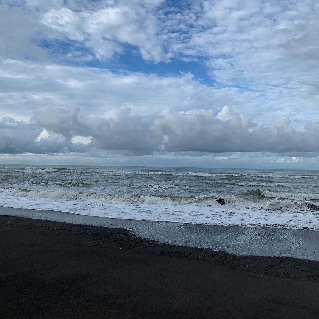 Black sand, waves, clouds.
